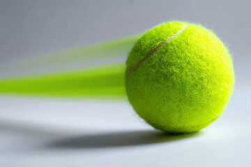 A close-up of a bright yellow tennis ball with motion blur on a white surface, highlighting its fuzzy texture and dynamic movement