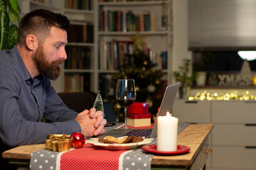 man working on laptop and sitting in office decorated with christmas tree and lights  festive ornaments.