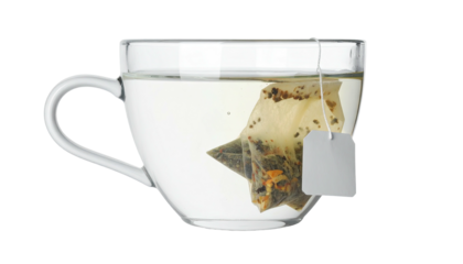 Clear glass teacup filled with light-colored liquid, holding a tea bag with a tag
