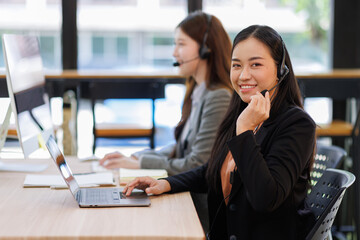 Call center, in headphones. two asian women are working in the office.
