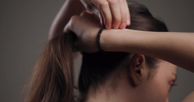 Woman tying her hair into a ponytail, a daily beauty routine captured