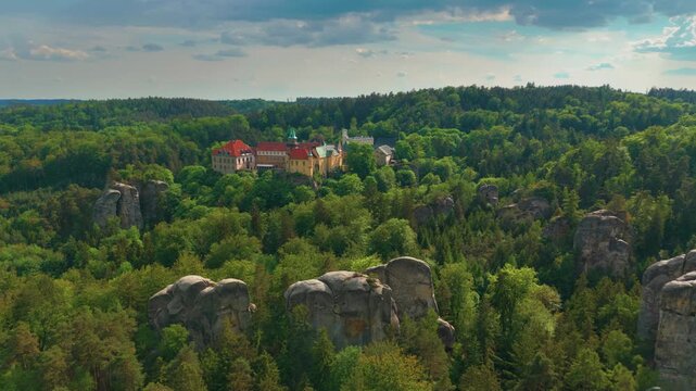aerial perspective captures the majestic Hrub&aacute; Sk&aacute;la Castle nestled amidst the dramatic sandstone rock formations of the Bohemian Paradise Česk&yacute; r&aacute;j region in the Czech Republic.