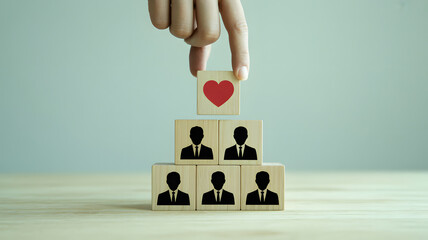 Hand placing heart on top of team members representing love, care, and support in a business, symbolizing teamwork and leadership