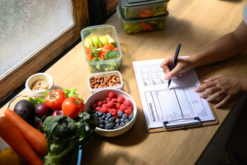 Closeup woman dietitian working on nutrition facts with different healthy food ingredients, Weight loss and right nutrition concept