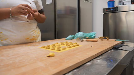 Close up shot of hands meticulously crafting delicate tortellini pasta in a bright professional kitchen with passion and focus showcasing small business dedication to authentic Italian cuisine