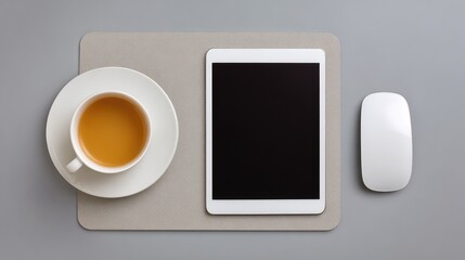 Minimalistic workspace with a tablet, white mouse, cup of tea, and gray mat, perfect for remote work or creative brainstorming sessions at home or in office settings