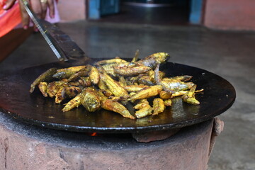 Small Snakehead or Channa orientalis Fish being fried in a pan. Fish are typically marinated with spices like turmeric, salt, and chili powder before being deep fried until they are crispy and golden.