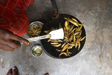 Small Snakehead or Channa orientalis Fish being fried in a pan. Fish are typically marinated with spices like turmeric, salt, and chili powder before being deep fried until they are crispy and golden.
