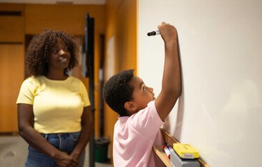 Afro black teacher and schoolboy creating new things on a whiteboard, homeschooling education