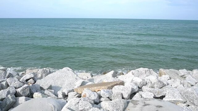 video of waves and large rock walls on the coast. Rock walls are made to prevent erosion on the shore with large rocks arranged along the coast