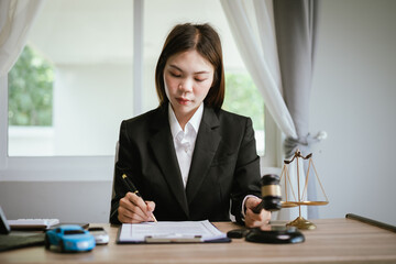 Female lawyer reviewing legal documents at office desk with gavel, justice scale, and contract papers, symbolizing law, judgment, and legal consulting.