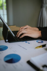 Businesswoman analyzing financial charts with calculator and documents on desk, working on business data and financial report in modern office.