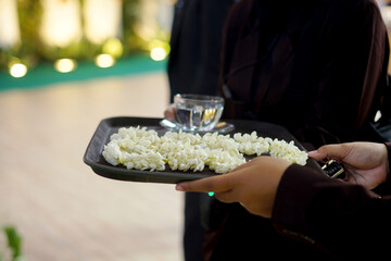 Elegant presentation of jasmine flowers (bunga melati) and a glass of water, highlighting traditions and ceremonies. This detail shot emphasizes Indonesian hospitality and event service