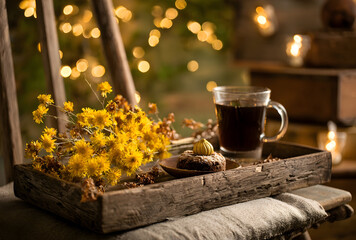 Still life with coffee, cake, and yellow flowers on a wooden tray with bokeh background on a chair