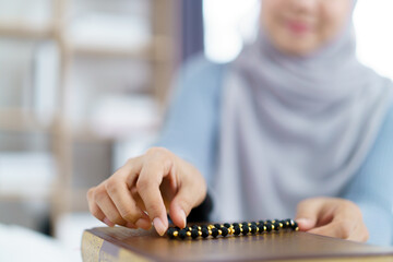 Fototapeta premium Muslim woman meditating and praying in morning light holding prayer beads.