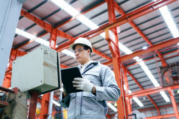 Naklejka premium Engineer checking control panel in factory, updating software with tablet.