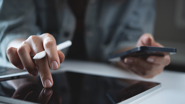 Woman using digital tablet and mobile phone, busy working at office, reading e-document, closeup. Freelancer, graphic designer online working via tablet pc on table, work at home, closeup - Powered by Adobe