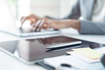 Close up, business woman working on laptop computer with digital tablet, stylus pen on table at office. Businesswoman surfing the internet, using laptop computer and tablet, business background