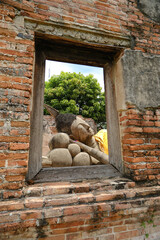 View of the Reclining Buddha outside through an ancient window at Wat Phutthaisawan, Ayutthaya, Thailand