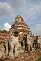 Ancient lion statue in front of the ruins of a pagoda at Wat Thammikarat, Ayutthaya