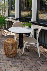Outdoor café seating with marble table, chairs, and woven stool, perfect for a relaxing break.