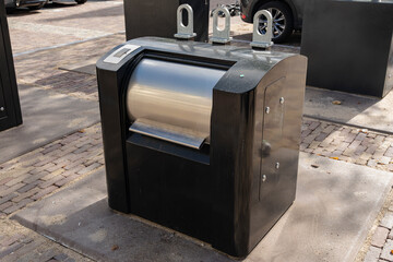 Automated public waste bin: A modern black receptacle featuring a cylindrical stainless steel opening.