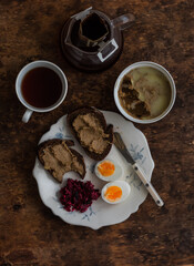 Delicious breakfast, snack - toasts with pate, boiled egg, beetroot salad and coffee on a wooden table, top view