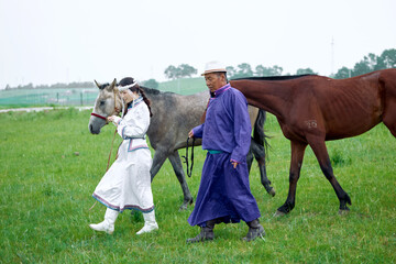 Mongolian herders father and daughter grazing on the grassland