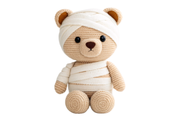 Beige crocheted bear completely wrapped in white gauze bandages with only face partially visible showing eyes, isolated on a transparent background