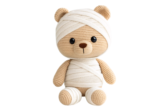 Tan crocheted teddy bear wrapped in white bandages like a mummy with visible round ears, isolated on a transparent background
