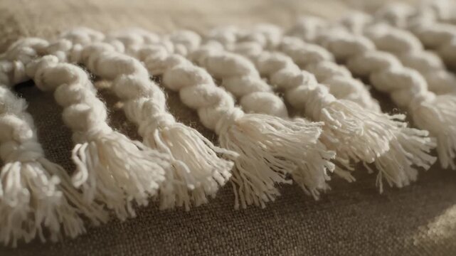 Cozy natural fiber textile with decorative macrame braid detail.