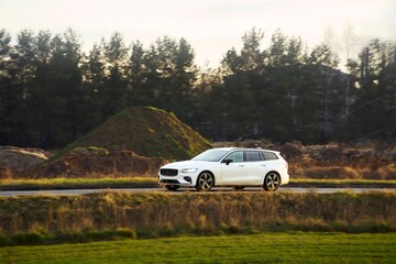 Obraz premium White electric car cruising rural area