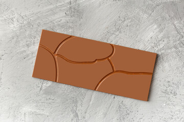 Chocolate with a beautiful pattern on a gray texture background, top view.