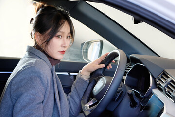 Asian beauty test driving a car in a 4S car dealership