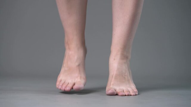Individual leg training on a gray studio background, bare feet, demonstrating foot position and stability
