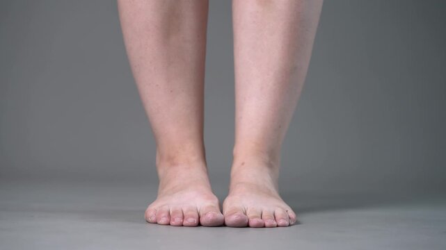 Individual leg training on a gray studio background, bare feet, demonstrating foot position and stability