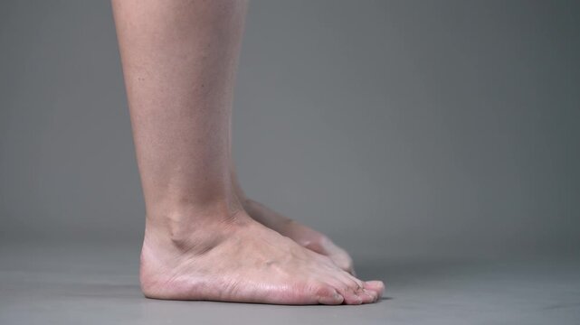 Individual leg training on a gray studio background, bare feet, demonstrating foot position and stability