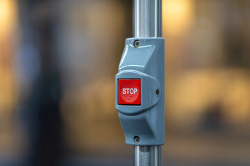 Close up of red STOP button on grey pole inside public transport