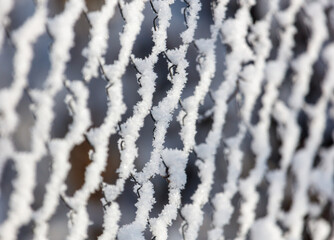 A snow covered fence with a mesh pattern