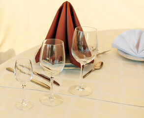 Three wine glasses are on a table with a napkin and a spoon