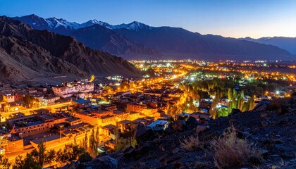 Nighttime Panorama of Illuminated Valley City Surrounded by Mountains and rocky Foreground