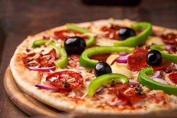 Pizza with chorizo ​​sausage, mozzarella cheese, green pepper and black olives. Rustic wooden background. Soft focus.	