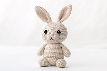 Obraz premium Cream-colored crocheted rabbit amigurumi with tall upright ears, large black eyes, pink embroidered nose, plump round body, arms and feet outstretched forward.