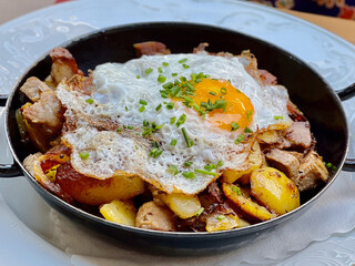 Tiroler Gröstl grostl with fried potatoes, pork, and fried egg on top