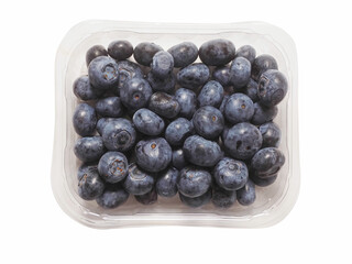 A plastic tray of blueberries sits on a white surface. The tray is clear and filled with fresh organic fruits ready for consumption. Healthy diet concept. Natural product.