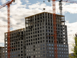 The process of monolithic frame construction for a new high-rise building, detailing the concrete structure and surrounding tower cranes at an active development site.