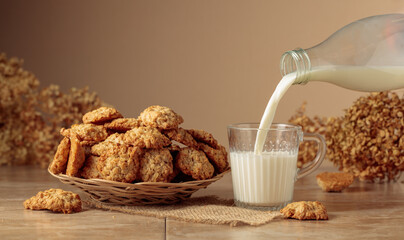 Oatmeal cookies and milk sit on a kitchen table.