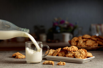 Oatmeal cookies and milk on a kitchen table.