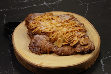 Classic baked croissant topping with cheese and sliced almond serving on the wooden plate. Famous starter and appetizer menu in coffee shop.