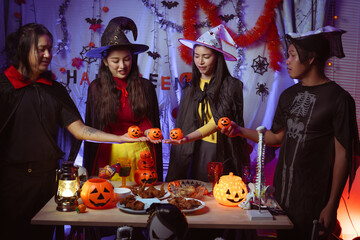 Asian man and woman celebrating Halloween, pumpkins at night, Halloween banner background for holiday activities.